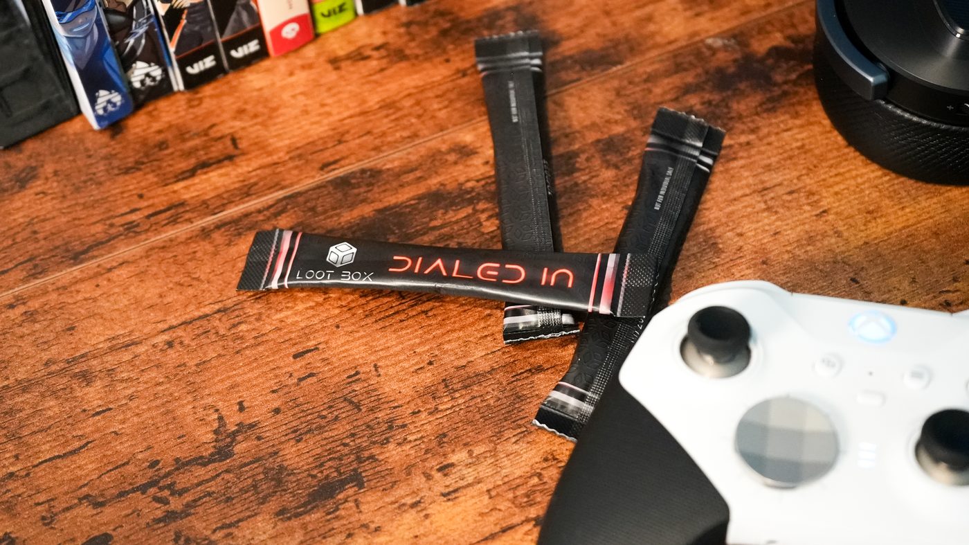 Dialed In stick packs laid out on a dark desk next to a game controller